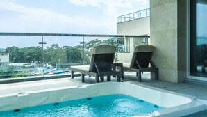A rooftop pool area with two lounge chairs and a hot tub. - DONGHO BEACH HOTEL (Gochang)