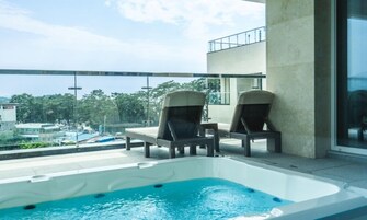 Zona de piscina en la azotea con dos sillas reclinables y un jacuzzi.