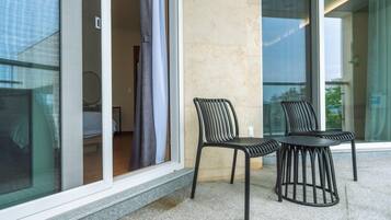 Ein modernes Hotelzimmer mit Balkon, ausgestattet mit zwei schwarzen Metallstühlen und einem kleinen Tisch.