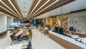 A modern cafe with a wooden reception desk, seating area, and a large TV screen. - DONGHO BEACH HOTEL (Gochang)
