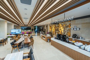 Una cafetería moderna con un mostrador de madera, zona de estar y una gran pantalla de televisión.