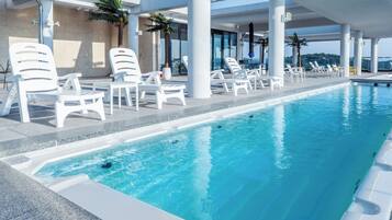 A swimming pool with white lounge chairs and palm trees.