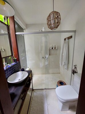 Un baño con cabina de ducha de vidrio, un lavabo blanco y un inodoro.