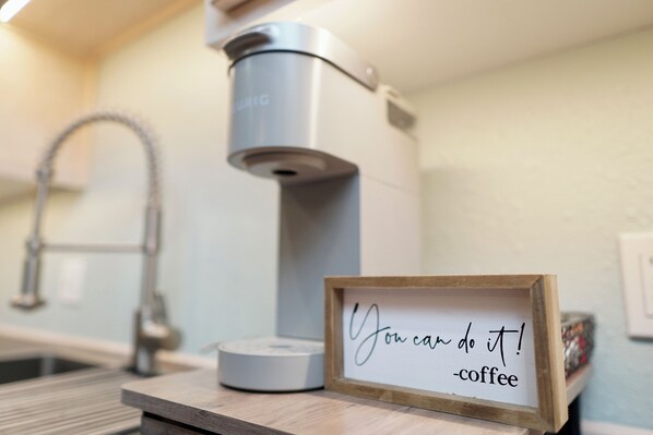 A coffee maker and a motivational sign in a kitchen setting.
