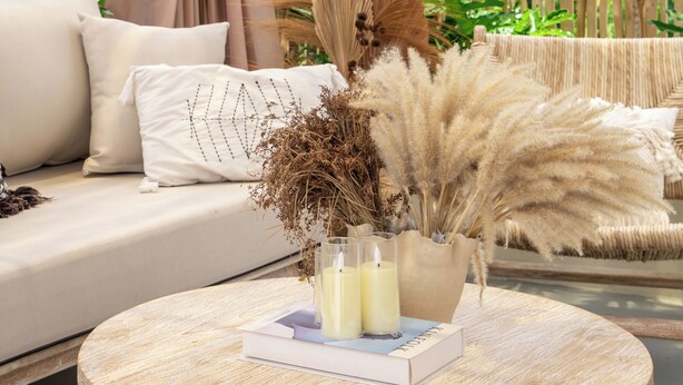 A round wooden table with a woven basket, a book, and two candles. - Gaia Villa by Betterplace (Canggu)