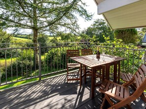 Guests can enjoy a tranquil outdoor space with a table and chairs overlooking the surrounding landscape.