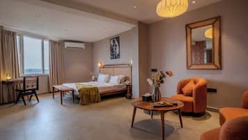 Ein Hotelzimmer mit Bett, Schreibtisch, Stuhl, rundem Couchtisch und großem Spiegel.