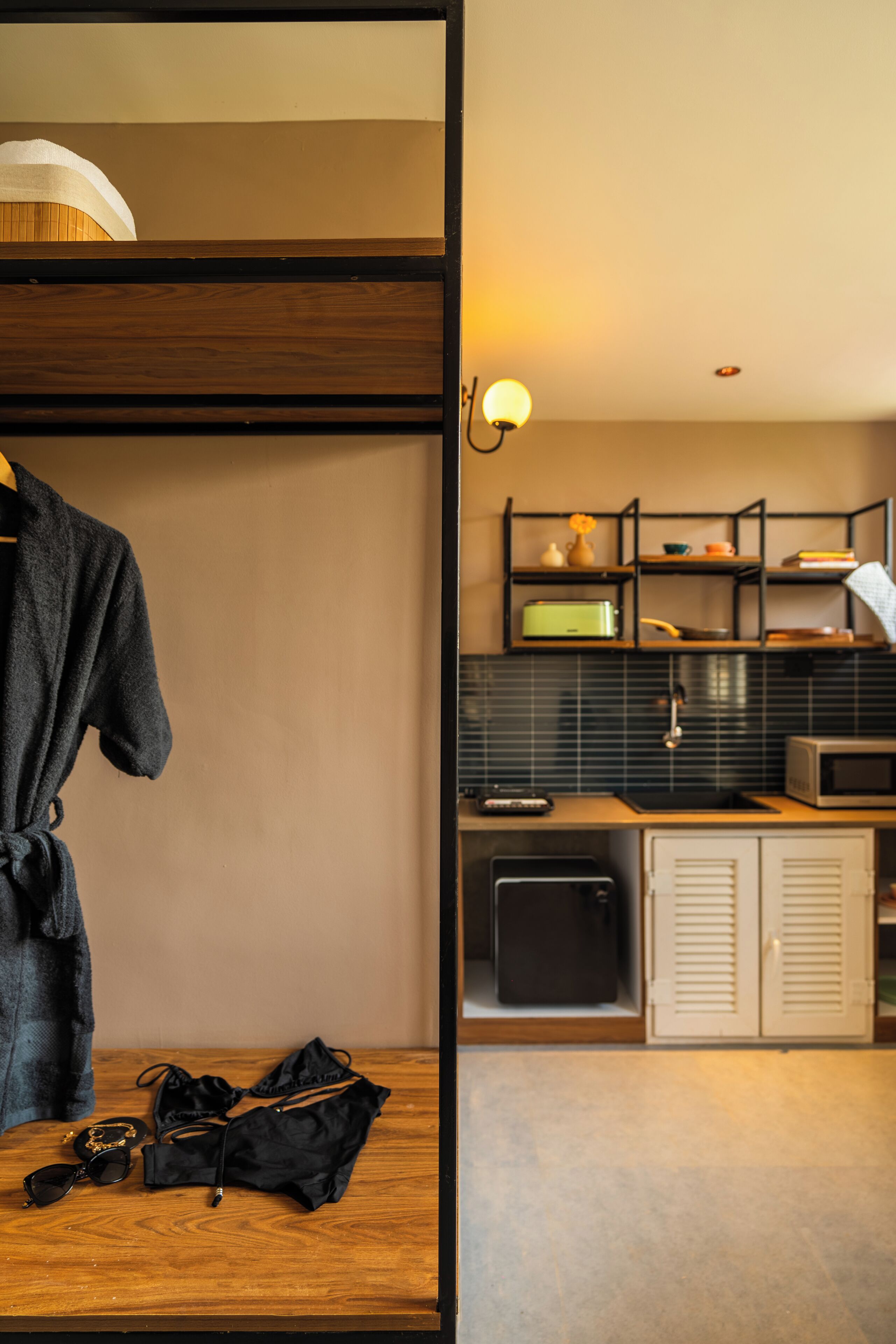 A room with a wooden vanity, a robe, a bag, and a small table with sunglasses.
