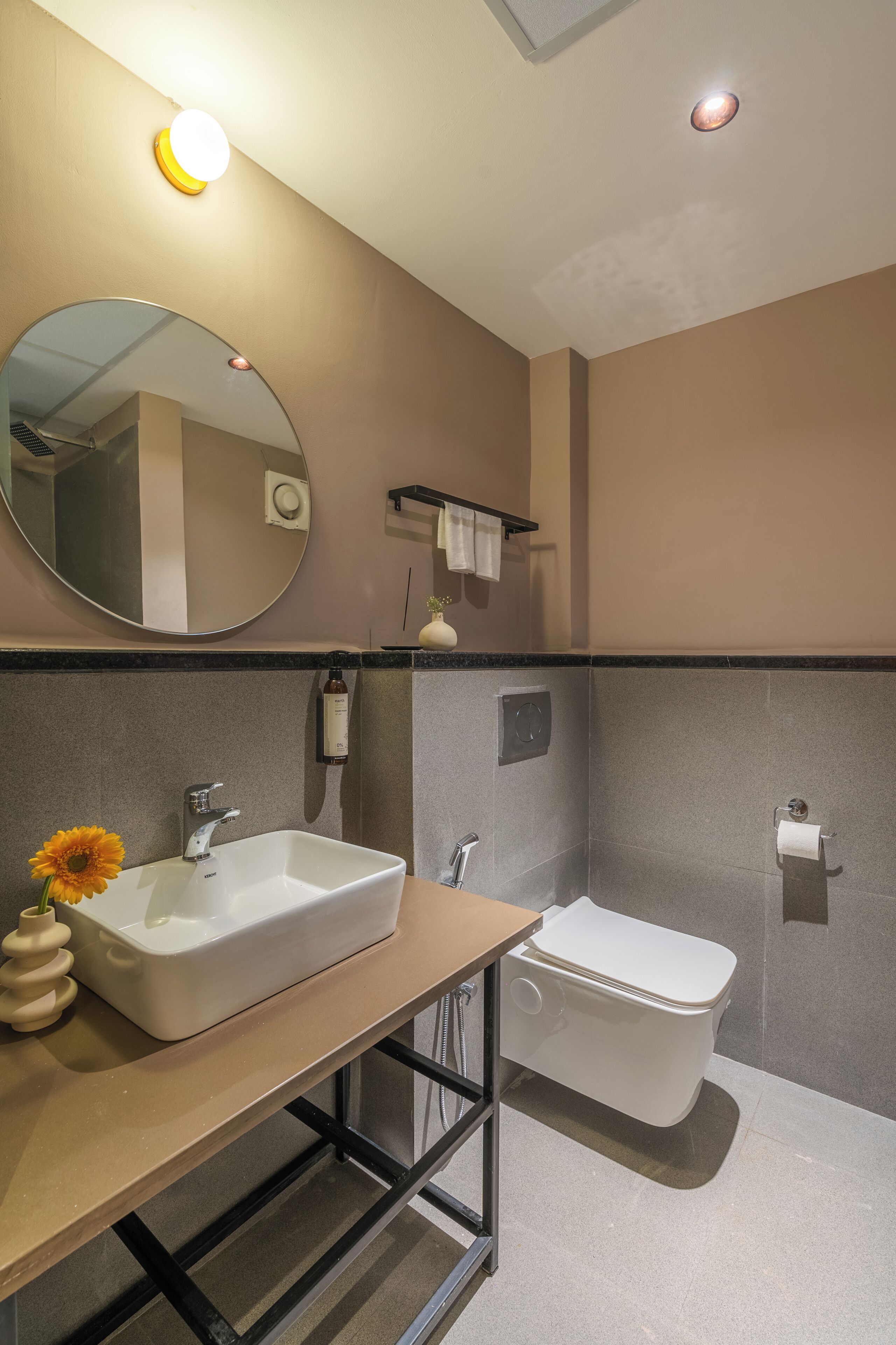 A modern bathroom with a large mirror, a white sink, and a toilet.