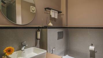 A modern bathroom with a large mirror, a white sink, and a toilet.