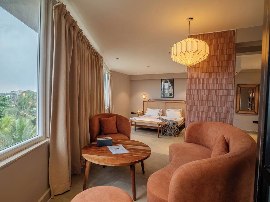 A hotel room with a bed, a sofa, a table, and a view of the city.