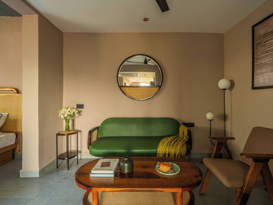 A room with a green sofa, a wooden coffee table, a small side table with a vase, a floor lamp, and a framed picture on the wall.