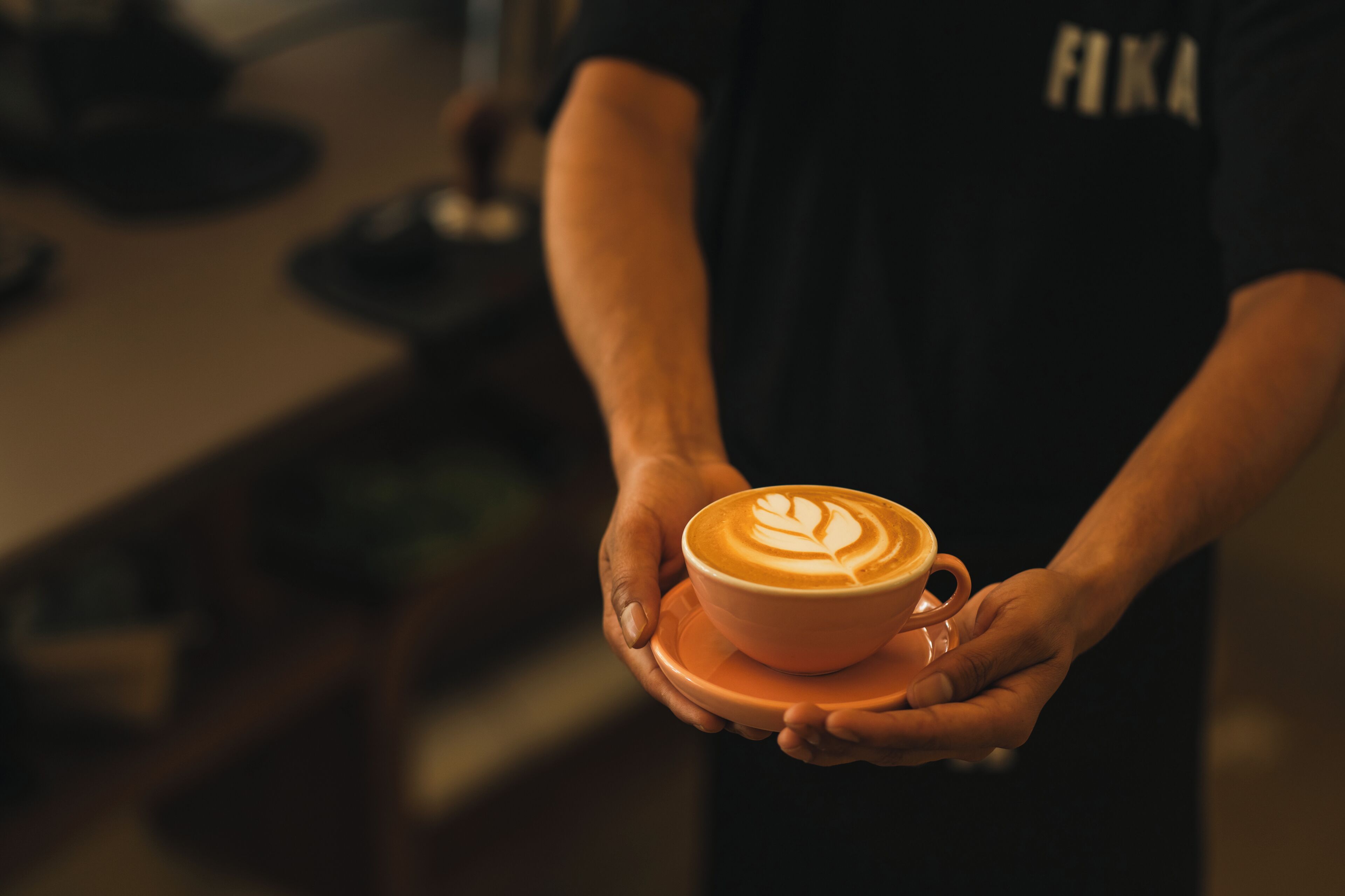 A person holding a cup of coffee with latte art.