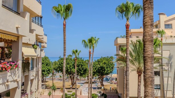A resort with multiple-story buildings, palm trees, and a view of the sea. - Montemar Puerto - Beachfront, Terrace, Swimming Pool. Sea Views (Torremolinos)