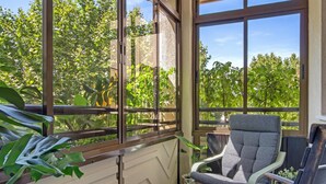 A sunlit room with large windows, a grey chair, and a potted plant. - Montemar Puerto - Beachfront, Terrace, Swimming Pool. Sea Views (Torremolinos)