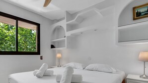 A modern bedroom with a large bed, white linens, a bedside table with a lamp, and a window with a view of greenery. - Montemar Puerto - Beachfront, Terrace, Swimming Pool. Sea Views (Torremolinos)