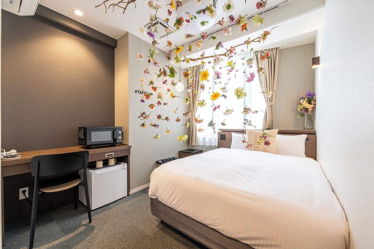 Habitación de hotel con cama, escritorio, silla y microondas.