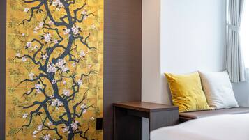 Una habitación de hotel con una cama grande, una mesita de noche y un papel tapiz floral en la pared.
