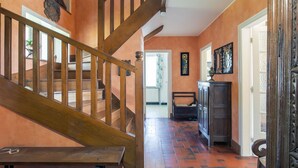 Un escalier en bois menant à un palier où se trouvent un banc et un meuble.