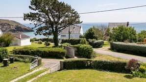 Une propriété située sur la côte, avec un grand arbre, une maison blanche et une vue sur la mer.