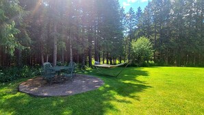 A forested area with a circular seating area and a hammock.