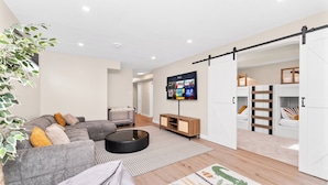 Uma sala de estar moderna com um sofá seccional, uma TV de tela plana, um armário com porta deslizante e um móvel de entretenimento de madeira.
