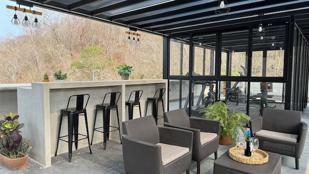 A covered outdoor seating area with wicker furniture, bar stools, and a bar counter. - Nabani Condominios T3 (Santa María Huatulco)