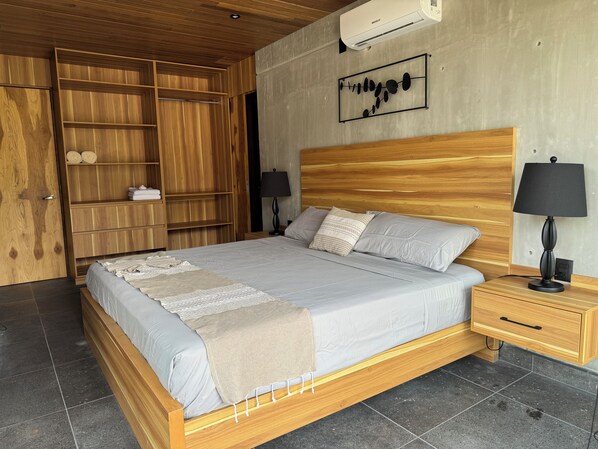 Ein Schlafzimmer mit einem hölzernen Bett, einem Nachttisch, einem Kleiderschrank und einer Wand-Klimaanlage.
