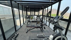A covered gym area with exercise equipment including dumbbells, a bench, and a treadmill. - Nabani Condominios T3 (Santa María Huatulco)