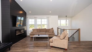 A modern living room with a black wall, a beige sofa, a coffee table, and a fireplace.