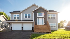 A two-story house with a front porch, two garages, and a well-maintained lawn.