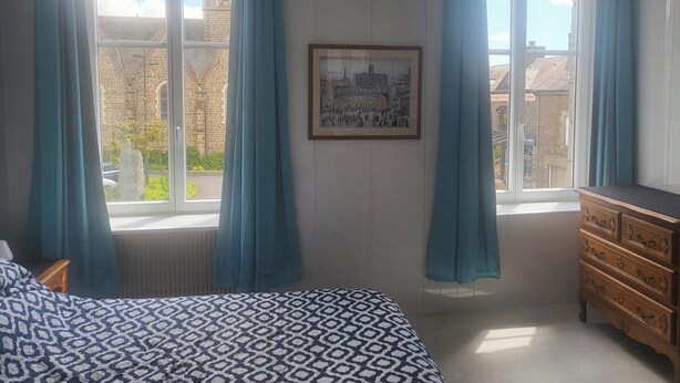 A bedroom with a bed, a dresser, a window with curtains, and a framed picture on the wall. - 1Bed Apartment Sleeps 2 - Parking, Wifi (Fougerolles du Plessis)