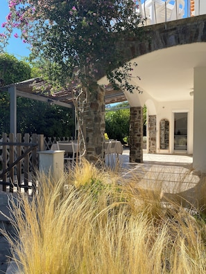 A covered outdoor seating area with stone pillars, a pergola, and a view of the property. - Loue Villa 8 Couchages à 3mm à Pied de la Plage,piscine,climatisé,cavalaire/mer (Cavalaire-sur-Mer)