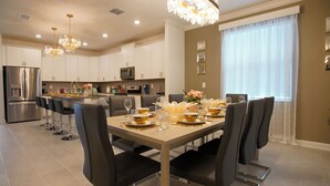 Una cocina moderna con armarios blancos, electrodomésticos de acero inoxidable y una zona de comedor con mesa para seis.