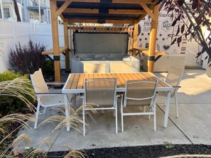 An outdoor patio with a wooden table and four chairs, a grill, and a wall with various designs. - Speakeasy, Hot tub, 1920s Family Beach Home (Atlantic City)