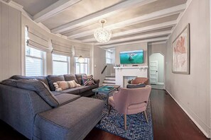 A living room with a grey sectional sofa, a pink armchair, a TV, and a fireplace.