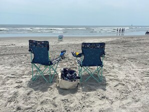 Relax on the beach with two comfortable chairs, overlooking the ocean.