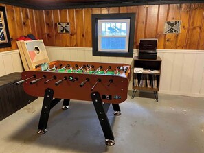 A foosball table in a room with wooden paneling and a window. - Speakeasy, Hot tub, 1920s Family Beach Home (Atlantic City)