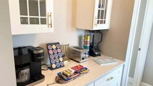 Una cocina con cafetera, tostadora y un soporte para tazas.
