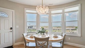 Comedor con ventanal panorámico, candelabro y vista a la playa.