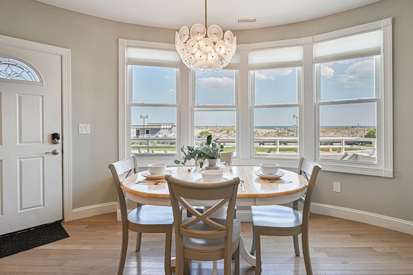 Enjoy meals with a view of the beach and golf course from this dining area with a round table for four.