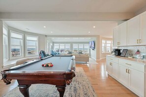 A spacious living area with a pool table, a sofa, and a television.
