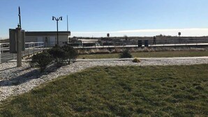 En bygning med fladt tag, et lille område med grus og græsplæne, og en klar himmel.