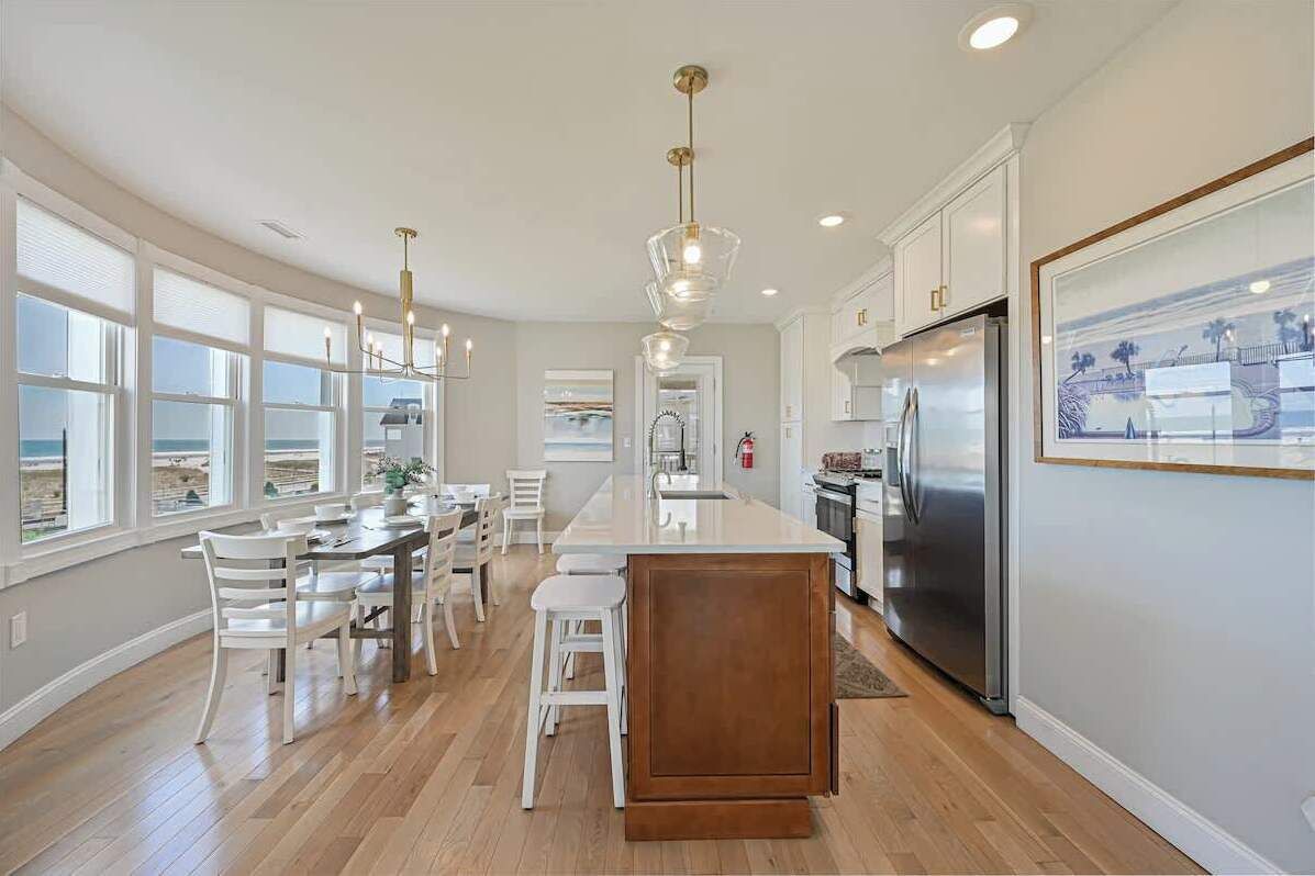 A spacious kitchen with a central island, white cabinetry, and a stainless steel refrigerator.