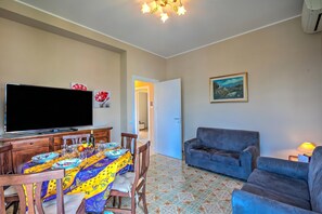 Un comedor con una mesa dispuesta para cuatro personas, un televisor y un sofá.