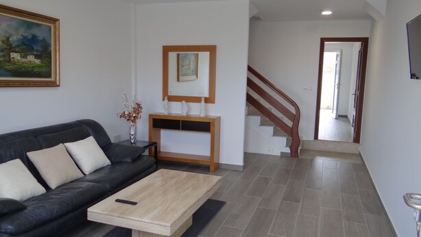 A living room with a black sofa, a wooden coffee table, and a painting on the wall. - House in Lira near the beach (Sofan (Santa Maria De Lira-Carnota))