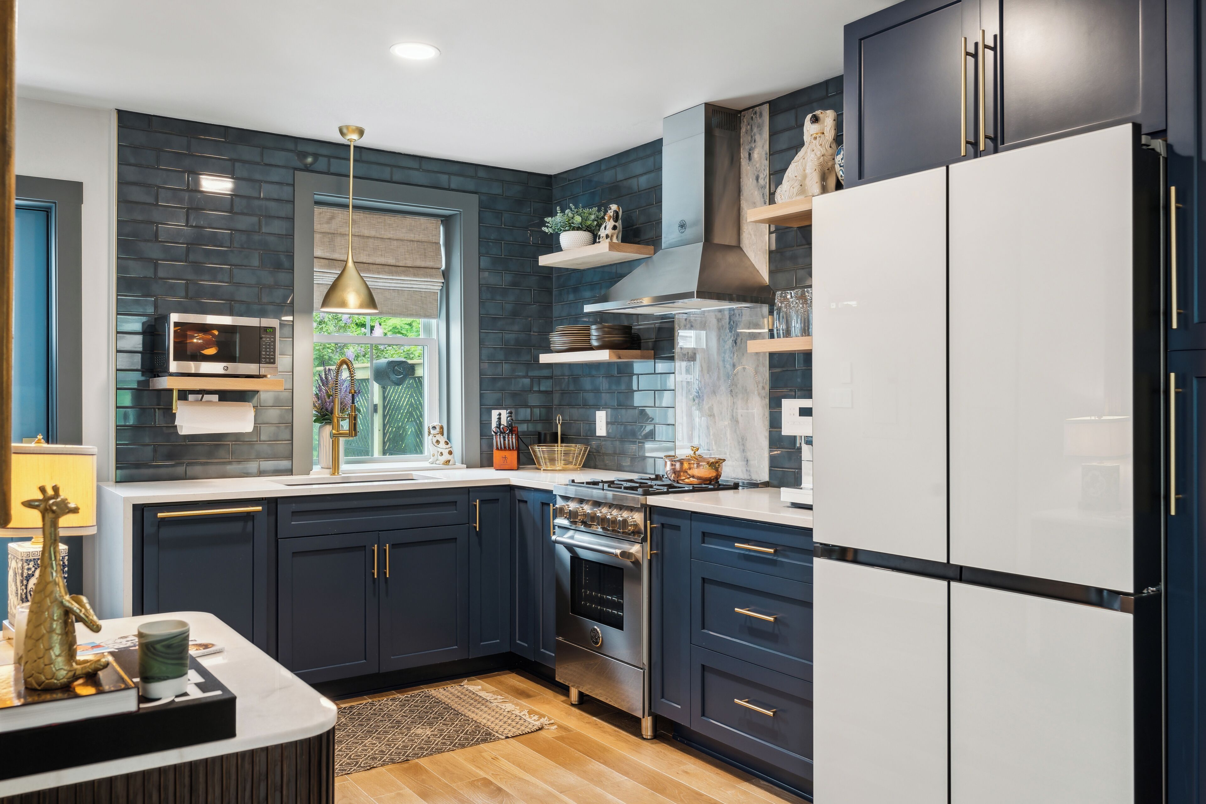 A modern kitchen with dark blue cabinets, a white refrigerator, and a stainless steel stove.