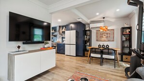 A modern kitchen with a flat-screen TV, built-in cabinets, and a dining area with a wooden table and chairs.