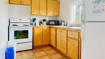 A kitchen with wooden cabinets, a white refrigerator, a microwave, and a stove.