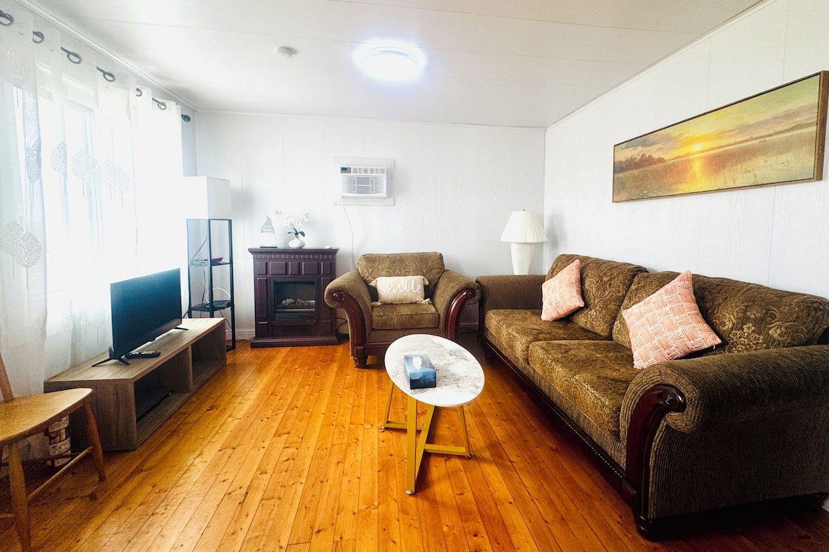A living room with a wooden floor, a sofa, a television, and a fireplace.